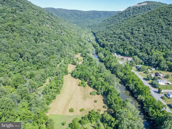 an aerial view of a residential houses with outdoor space and trees all around
