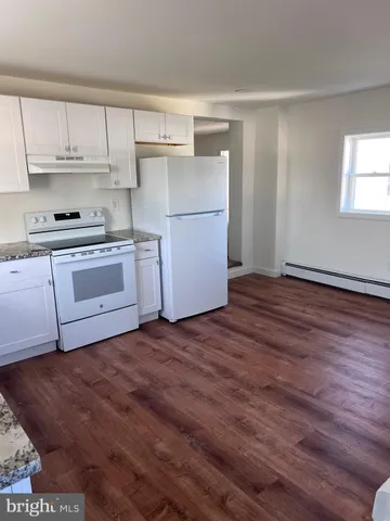 a kitchen with wooden floors and white appliances