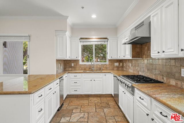 a kitchen with granite countertop white cabinets white appliances a sink and a window