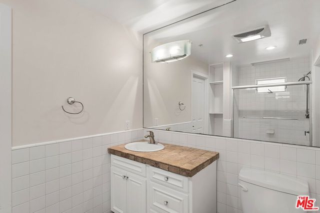 a bathroom with a granite countertop sink a toilet and shower