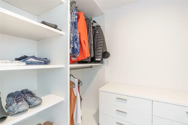 a view of walk in closet with clothes and shoes