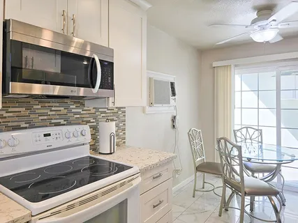 a kitchen with granite countertop white cabinets appliances and a dining table
