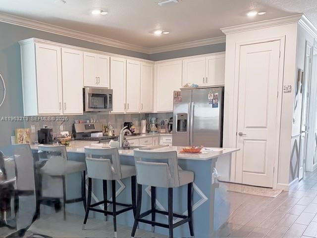 797 Bloomfield Road Port St. Lucie, FL 34984 - Photo 5 of 35 a kitchen with stainless steel appliances a table chairs refrigerator and a sink