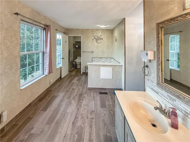 a spacious bathroom with a tub sink and mirror