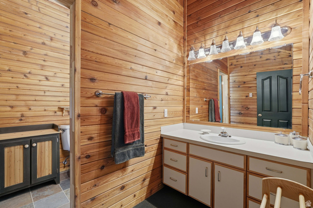 6 Beaver Springs Rancheros Oakley, UT 84055 - Photo 27 of 68 Bathroom featuring paneled wood walls, an extended vanity with an integrated sink, and a large mirror with overhead lighting