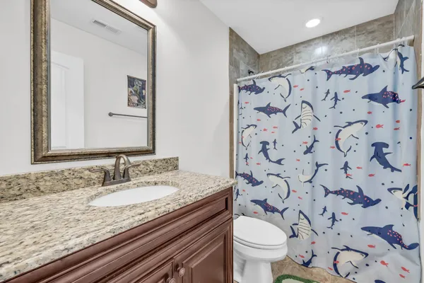 a bathroom with a granite countertop toilet a sink and a mirror