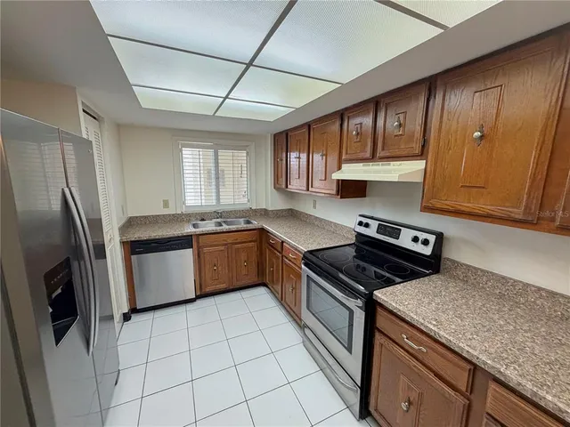 a kitchen with stainless steel appliances granite countertop a stove a sink dishwasher a refrigerator and cabinets with wooden floor