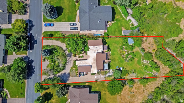 510 Spring Creek Road Providence, UT 84332 - Photo 85 of 97 Aerial view of a sprawling property featuring a main residence with a brown roof and light-colored siding, a paved circular driveway, established landscaping, and a large undeveloped natural area