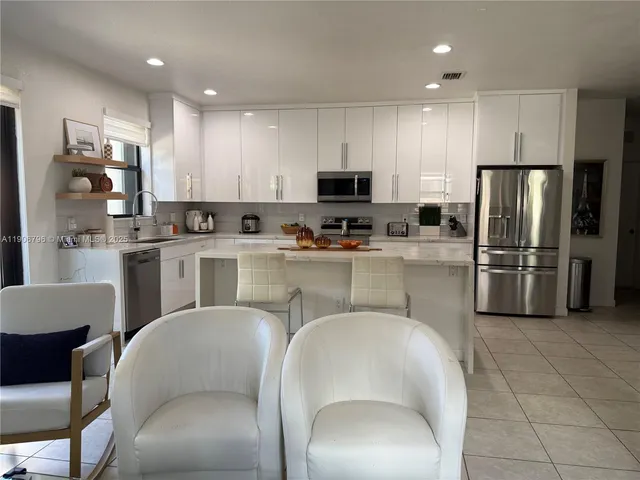 a kitchen with stainless steel appliances granite countertop a refrigerator a sink a stove a dining table and chairs