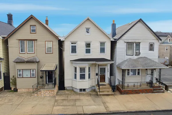 a view of a white house with large windows next to a road