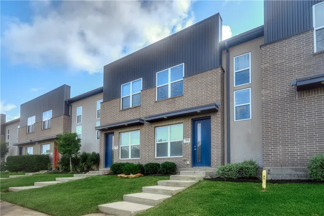 a view of a brick house with a yard and plants