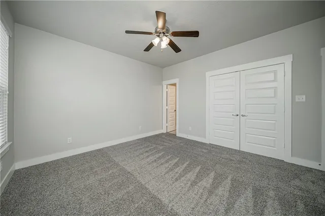 an empty room with closet and ceiling fan