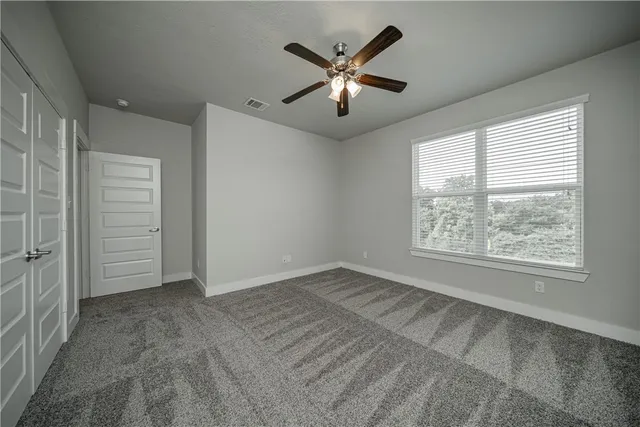 an empty room with fan and windows