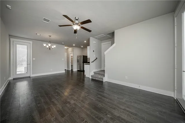 a view of an empty room with wooden floor a ceiling fan and windows
