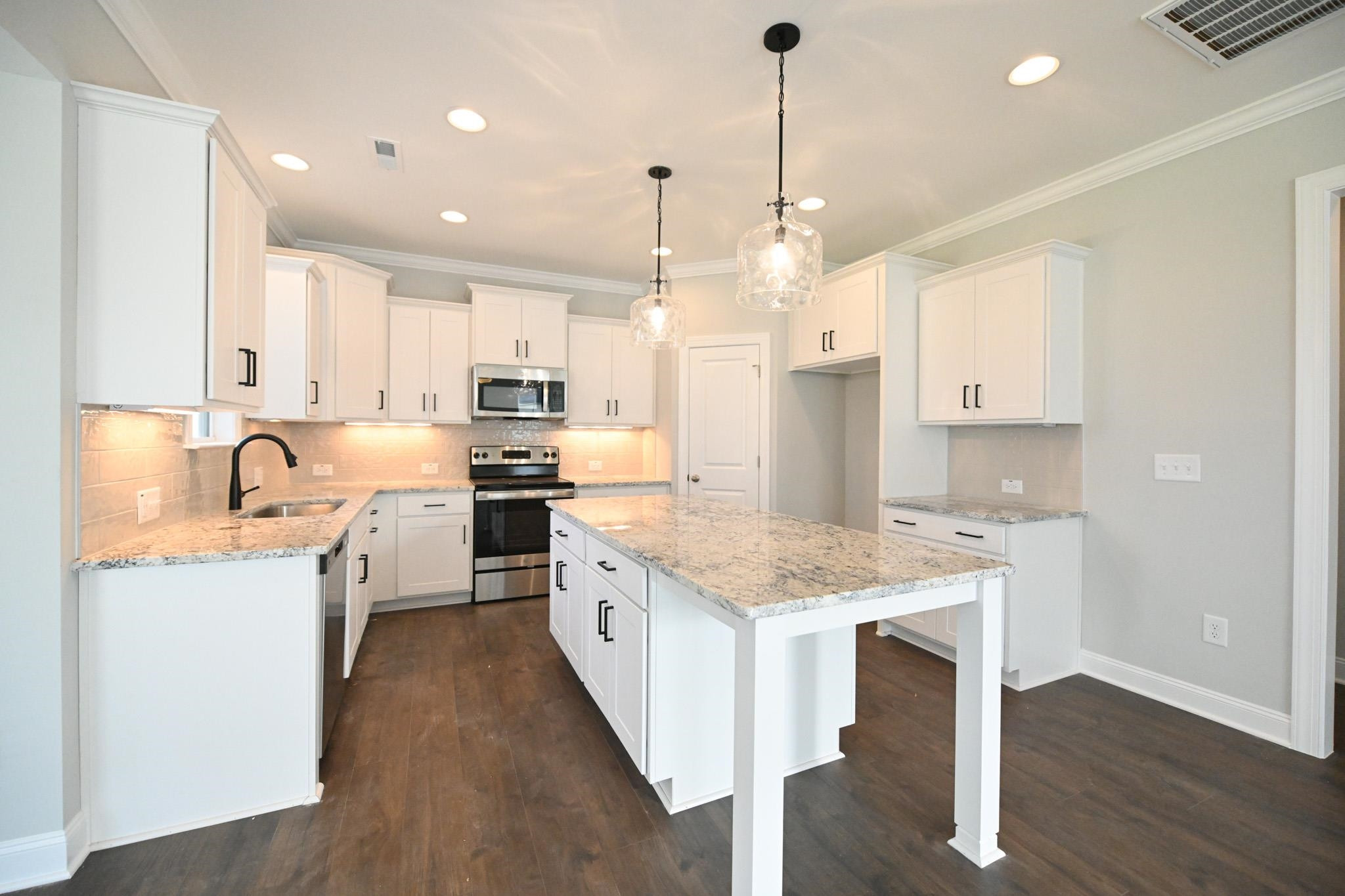 110 Freewill Place Raleigh, NC 27603 - Photo 12 of 39 a kitchen with stainless steel appliances kitchen island granite countertop a sink a stove a refrigerator and white cabinets with wooden floor