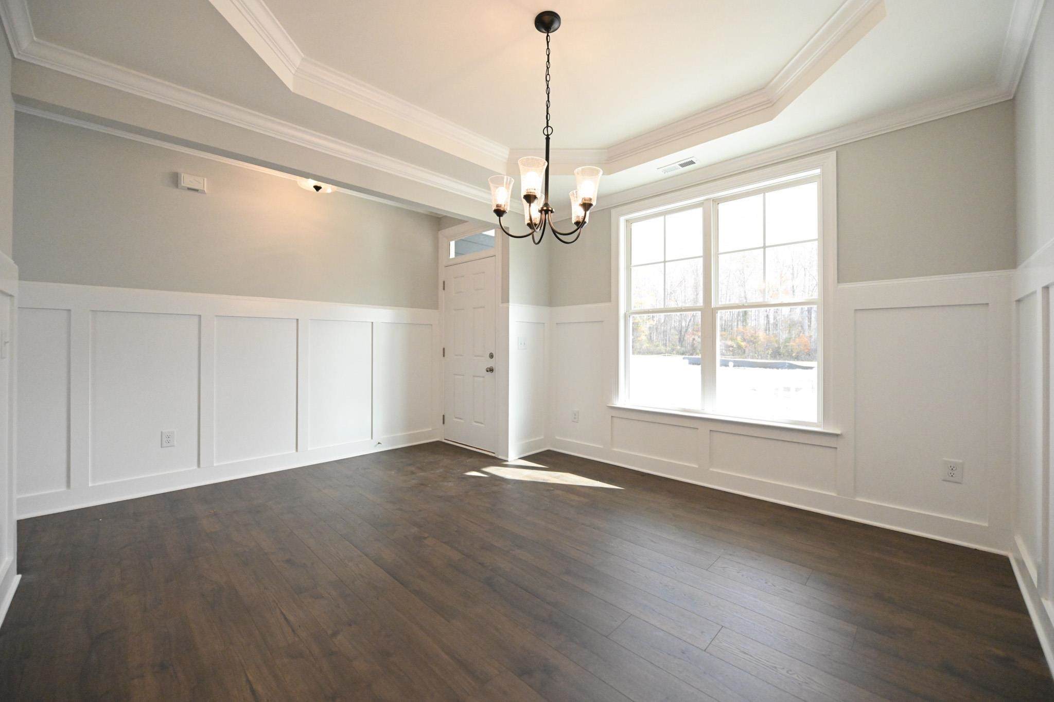110 Freewill Place Raleigh, NC 27603 - Photo 5 of 39 an empty room with wooden floor chandelier and windows
