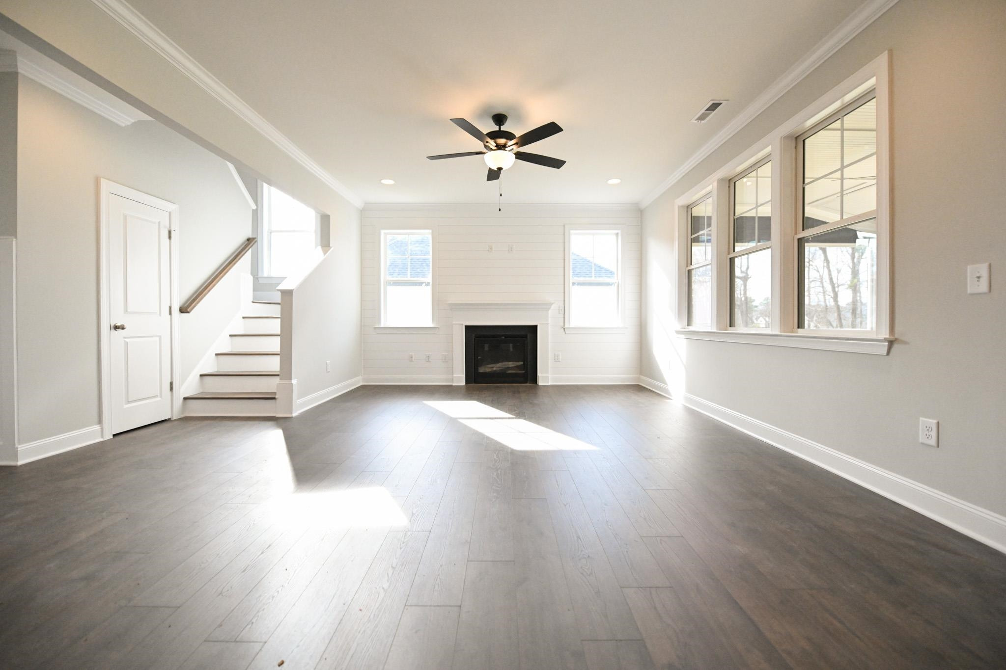 110 Freewill Place Raleigh, NC 27603 - Photo 7 of 39 an empty room with wooden floor fan and windows