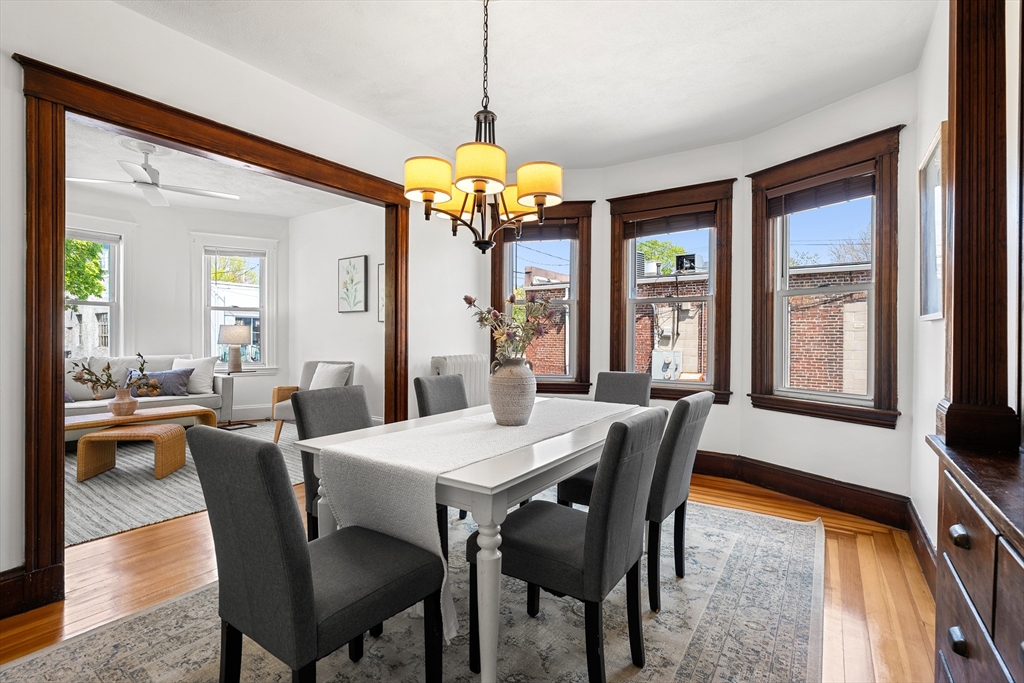2 Thorndike Street, Unit 2 Arlington, MA 02474 - Photo 8 of 22 a dining room with wooden floor a chandelier a wooden table and chairs