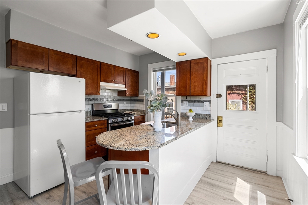 2 Thorndike Street, Unit 2 Arlington, MA 02474 - Photo 10 of 22 a kitchen with stainless steel appliances granite countertop a refrigerator a stove a sink a dining table and chairs