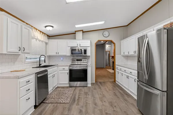 an empty room with wooden floor chandelier and windows