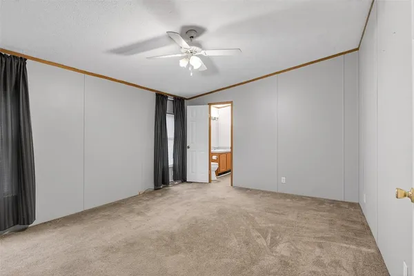 an empty room with a chandelier fan and windows