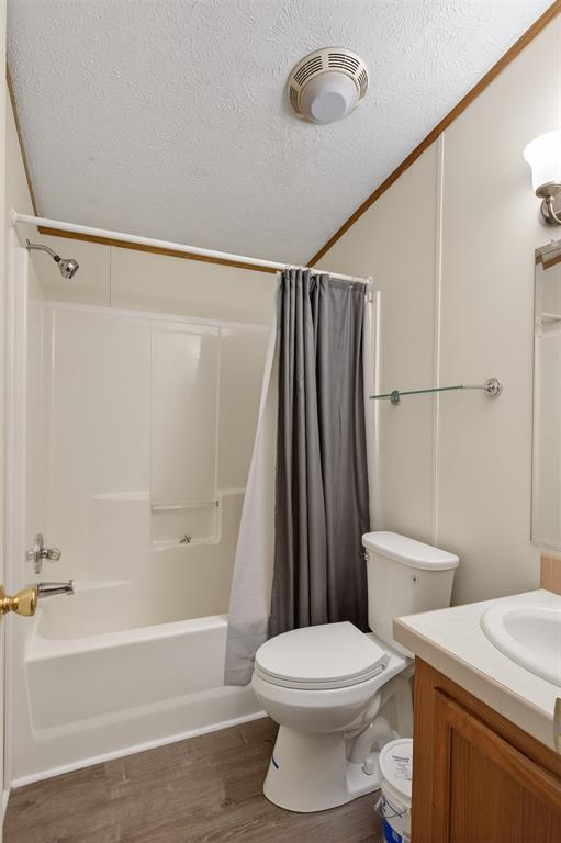1202 Princeton Road Princeton, LA 71067 - Photo 27 of 32 Bathroom featuring vanity, wood finished floors, crown molding, shower / bath combo with shower curtain, and a textured ceiling