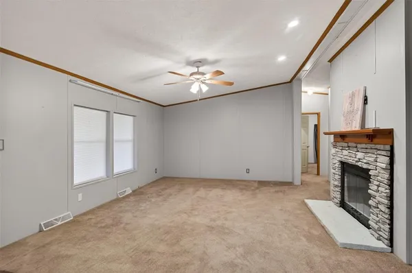 a view of an empty room with a fireplace and a ceiling fan