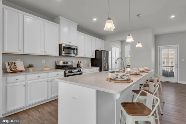 a kitchen with stainless steel appliances granite countertop a sink a stove a microwave a refrigerator and white cabinets