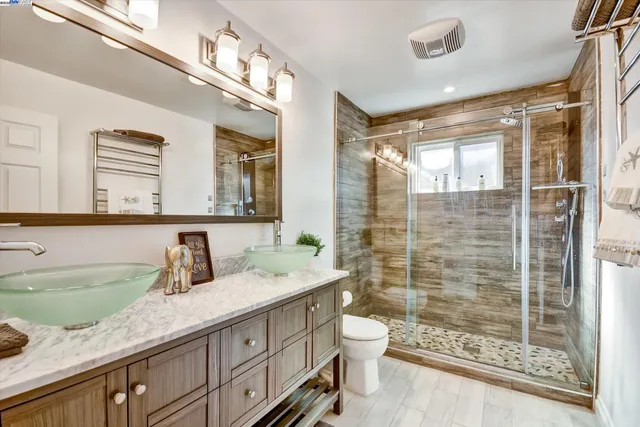 a bathroom with a granite countertop sink a toilet a mirror and shower