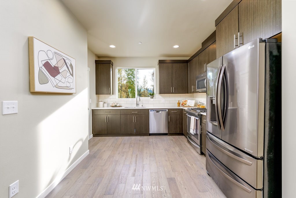 4227 Northeast 3rd Lane Renton, WA 98059 - Photo 3 of 40 a kitchen with stainless steel appliances a refrigerator sink and wooden floor