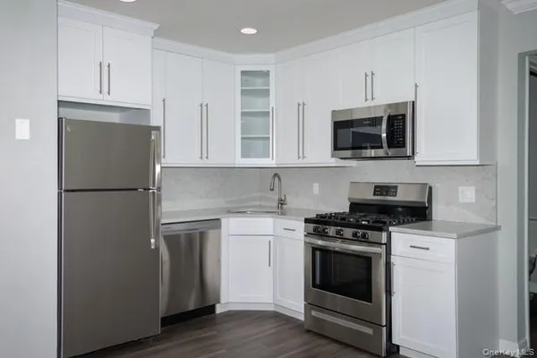 a kitchen with cabinets stainless steel appliances and wooden floor