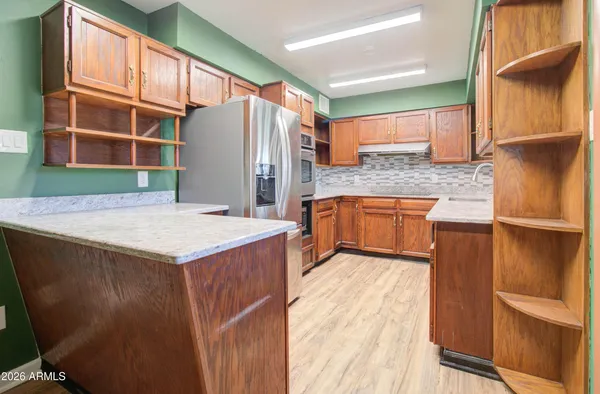 a living room with stainless steel appliances kitchen island granite countertop a refrigerator a stove and a wooden floors