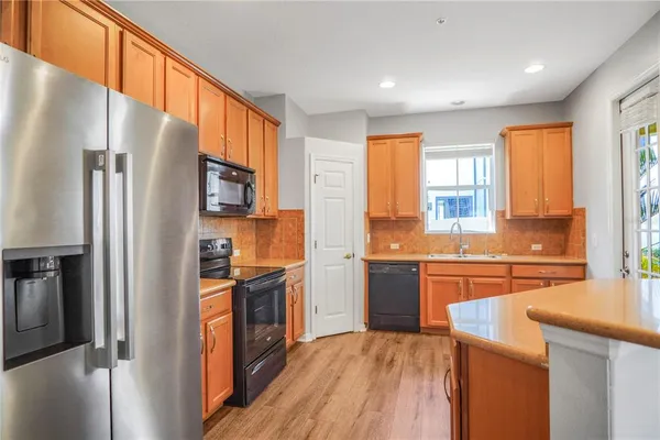 a kitchen with stainless steel appliances granite countertop a sink and cabinets with wooden floors