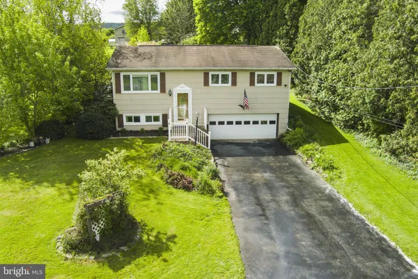a view of a house with a small yard and large trees