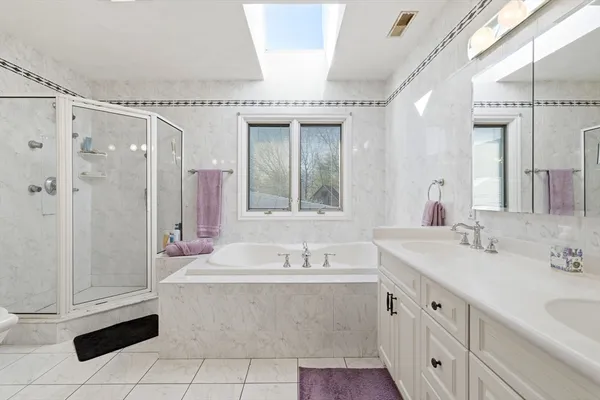 a bathroom with a tub a sink and a large mirror