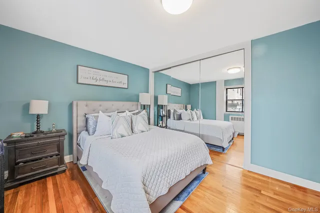 a bedroom with bed and a dresser with wooden floor