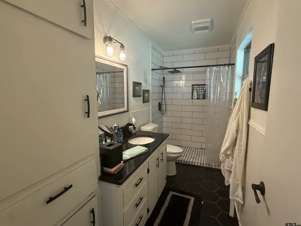 a bathroom with a sink a toilet a mirror and shower