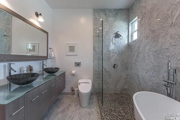 a bathroom with a granite countertop toilet a sink a mirror and shower