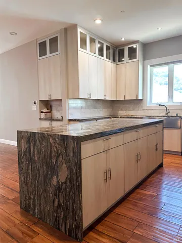 a kitchen with stainless steel appliances granite countertop a sink a stove and a wooden floors