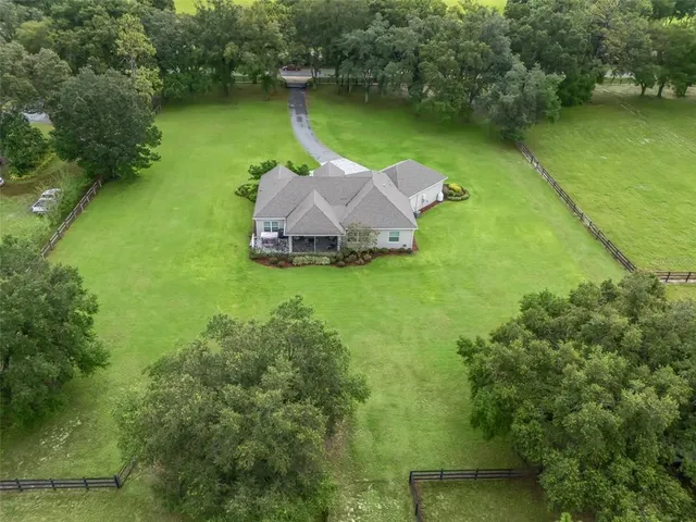 an aerial view of residential houses with outdoor space and trees