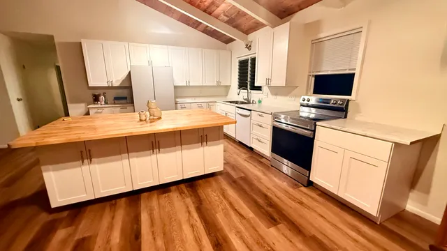 a large kitchen with a sink and dishwasher a stove top oven with wooden floor