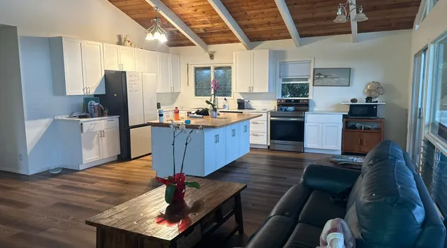 a kitchen with stainless steel appliances granite countertop a refrigerator a stove top oven a sink dishwasher and wooden cabinets with wooden floor