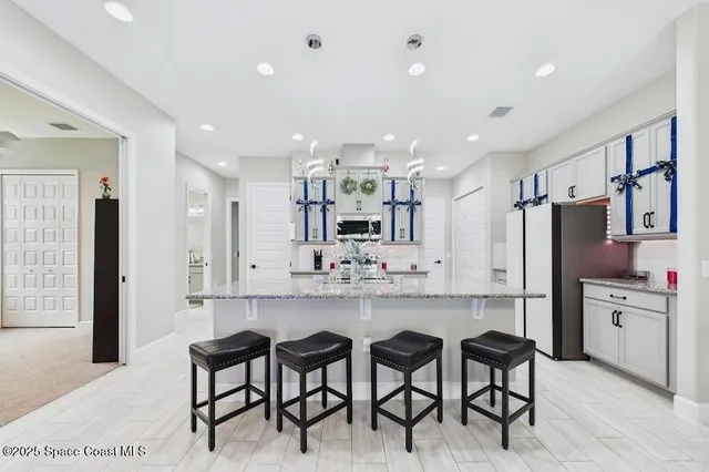 a large kitchen with cabinets chairs and stainless steel appliances