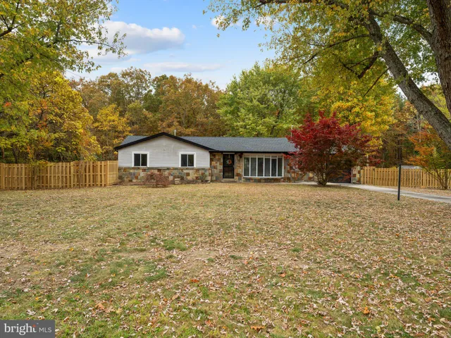 a backyard of a house with large trees and wooden fence