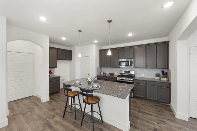 a kitchen with kitchen island a stove a table and chairs in it