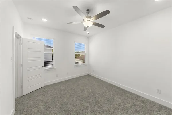 an empty room with ceiling fan and window