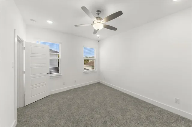 an empty room with ceiling fan and window