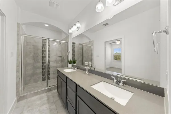 a bathroom with a double vanity sink mirror and shower