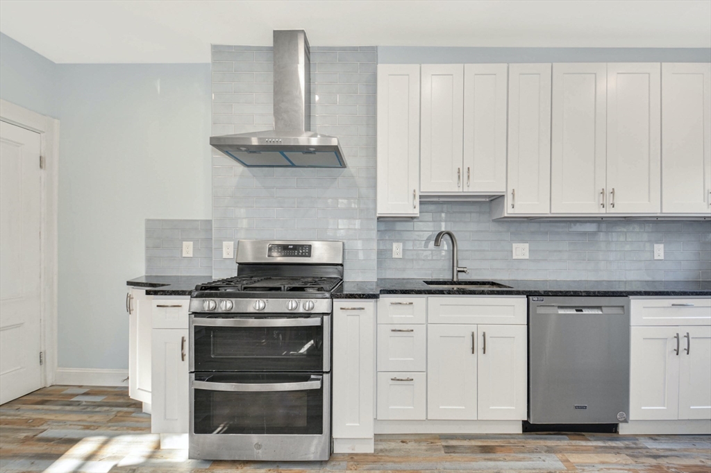 10 Middle Street, Unit 10 Newton, MA 02458 - Photo 5 of 19 a kitchen with granite countertop white cabinets and stainless steel appliances