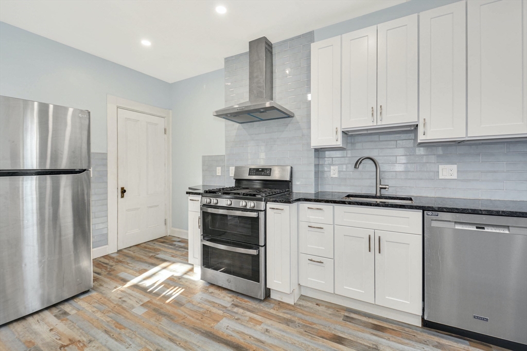 10 Middle Street, Unit 10 Newton, MA 02458 - Photo 7 of 19 a kitchen with granite countertop a refrigerator stove and white cabinets